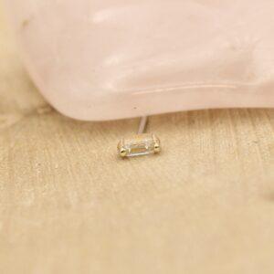 Kleine gouden Buddha bedel met heldere details op houten ondergrond.