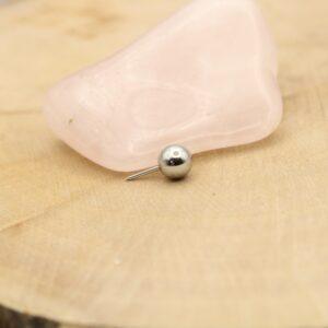 Metaal ballet met naald op roze rozenkwarts steen, close-up.