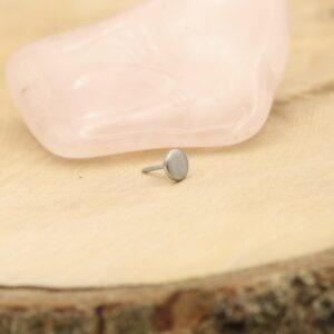 Close-up van een NeoMetal Disc oorbel op een houten oppervlak.