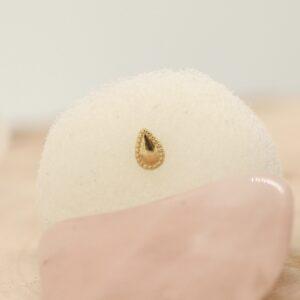 Close-up van een zilveren oorbel met gouden accent op een zachte achtergrond.